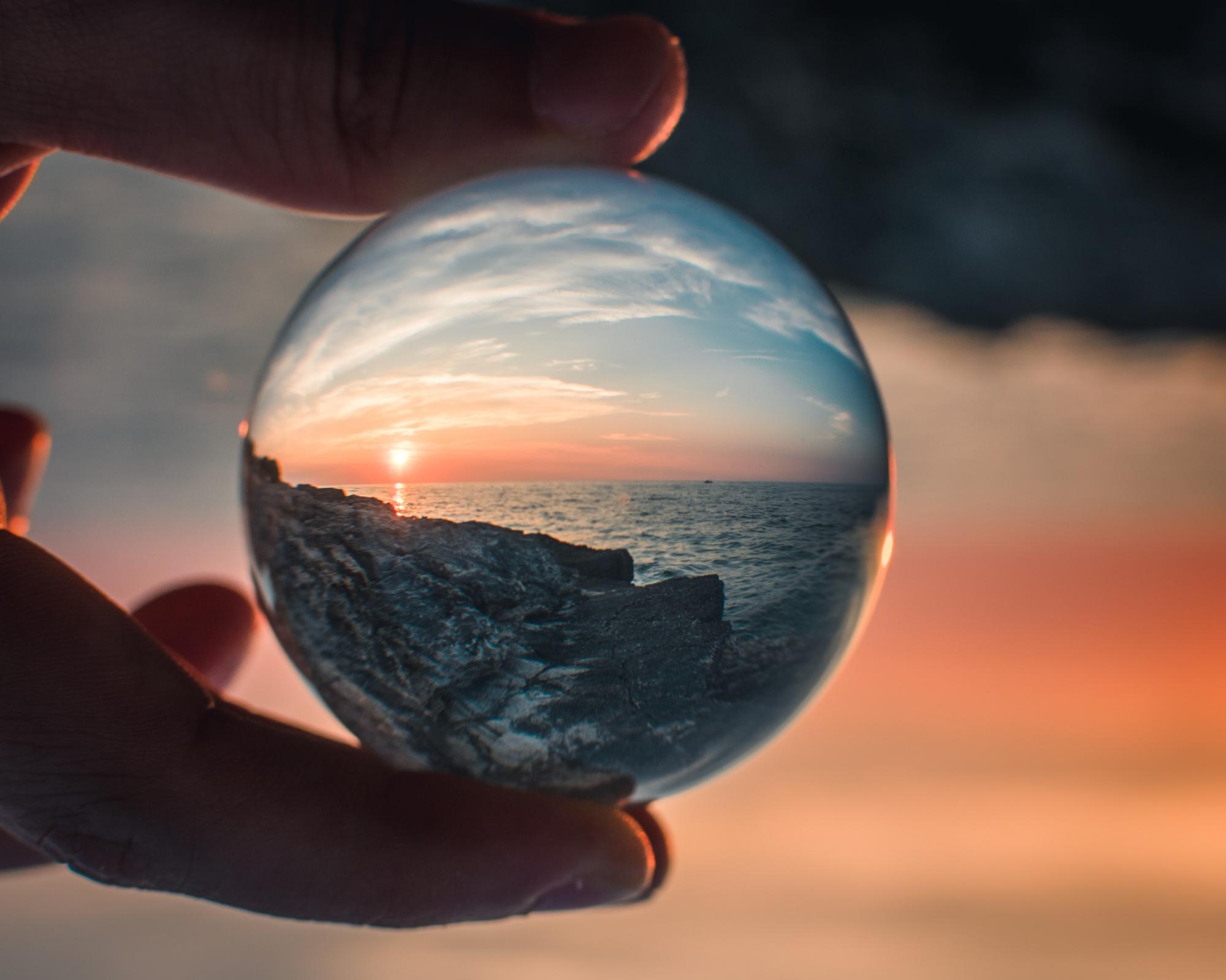 person holding round clear glass ball photo by Tadeusz Lakota